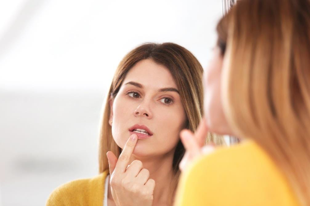 Women looking into a mirror touching her lip