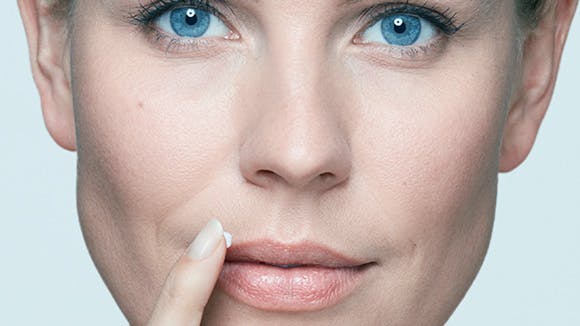 Close up of woman applying Abreva cream to her lip
