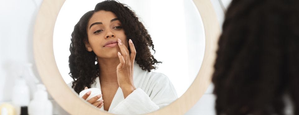 Woman touching upper lip while looking in the mirror