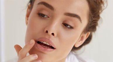 Woman applying lip balm in mirror