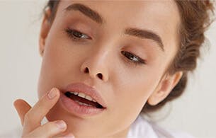 Woman applying lip balm in mirror