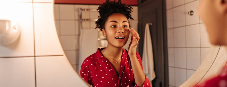 Young woman looking in the bathroom mirror