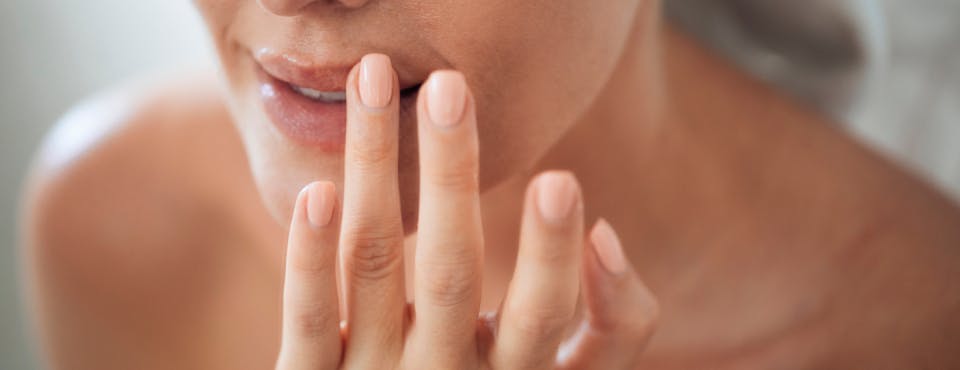 Close-up of woman applying lip balm with finger