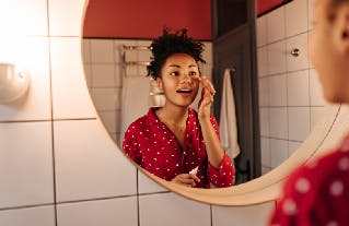 Young woman looking in the bathroom mirror