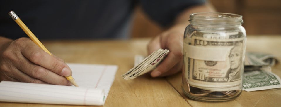 Stress Busting Money Tips - A man counting his savings in a jar