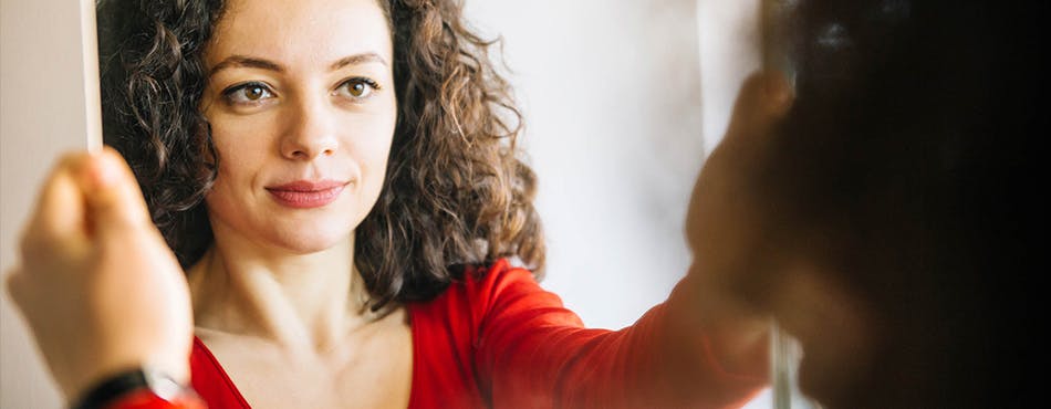 Woman looking at face in mirror Woman looking at face in mirror
