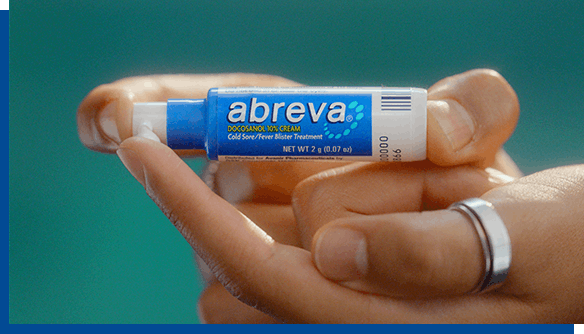 Person with ring on finger holding Abreva Cold Sore Cream pump