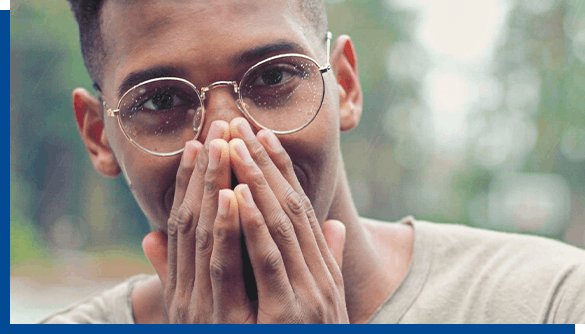 Man in glasses covering his mouth with hands to hide cold sores