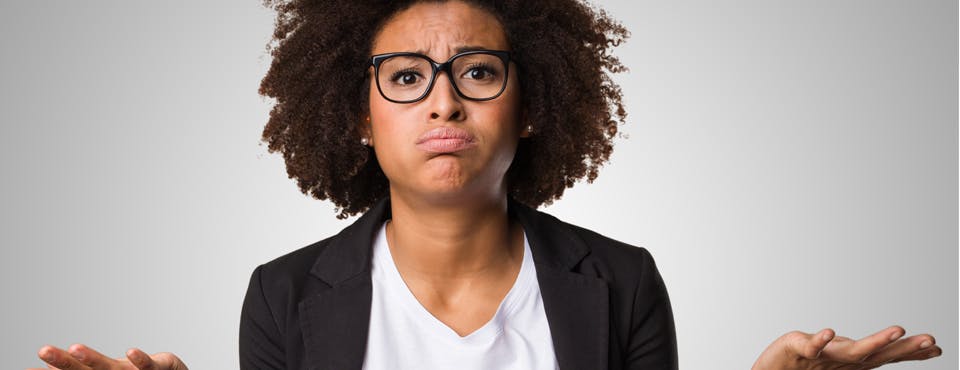 black woman in jacket and glasses looking confused