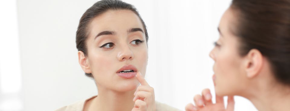 Young woman looking at her lips in the mirror