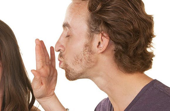 Un homme qui s’apprête à embrasser une femme qui l’arrête de la main