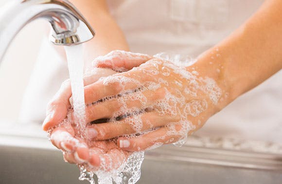 Une personne se lave les mains au lavabo