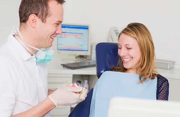 Un professionnel des soins dentaires et une patiente discutent en souriant
