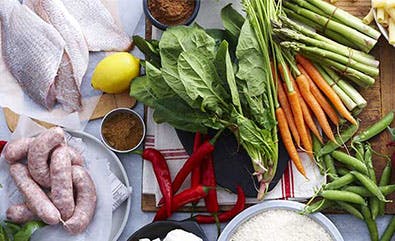 Divers légumes, saucisse et poisson crus disposés sur une table