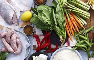 Divers légumes, saucisse et poisson crus disposés sur une table