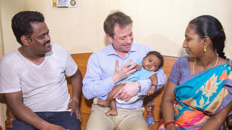 People holding baby with cleft lip.