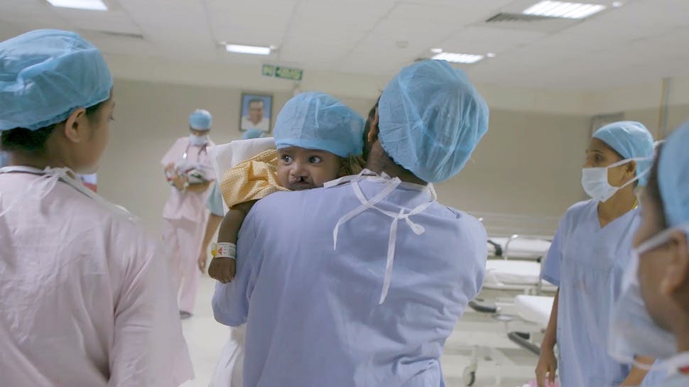 Medical staff holding baby with cleft lip.