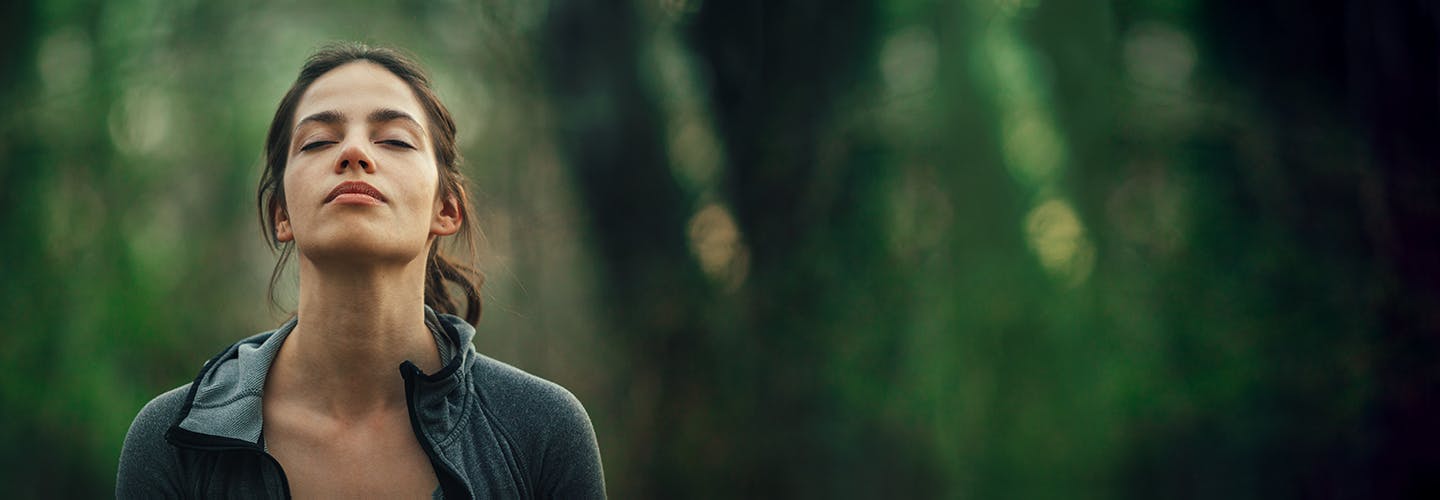 Woman breathes freely in a forest with a decongested nose.