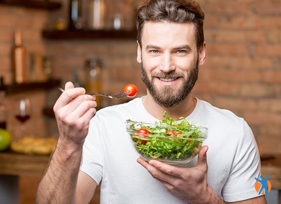 Man eet gezonde salade in zijn keuken thuis