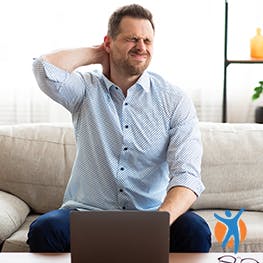 Person fasst sich an den schmerzenden Nacken.