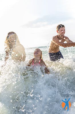 Frau spielt mit Kindern im Meer
