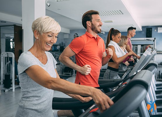 Gruppe von Menschen in einem Fitnessstudio, die auf einem Laufband laufen, um sich fit zu halten