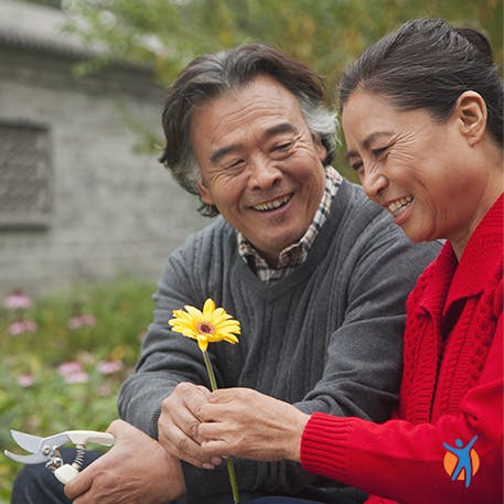 Ein älterer Herr reicht einer Frau eine Blume