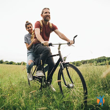 Frau und Mann fahren Fahrrad auf einer Wiese ohne Schmerzen