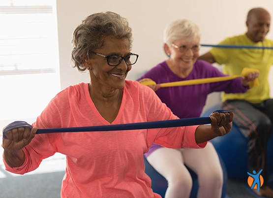 Gruppe älterer Damen bei Übungen mit dehnbaren Übungsbändern