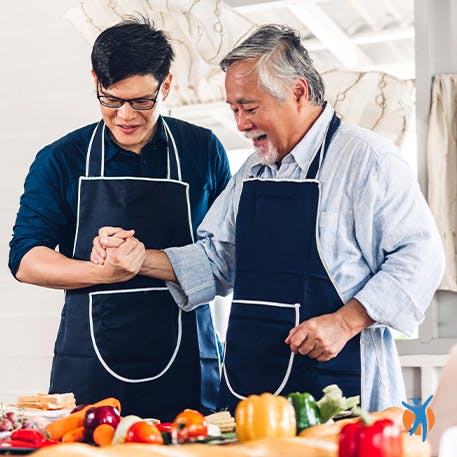 Zwei Männer tragen Kochschürzen beim Kochen