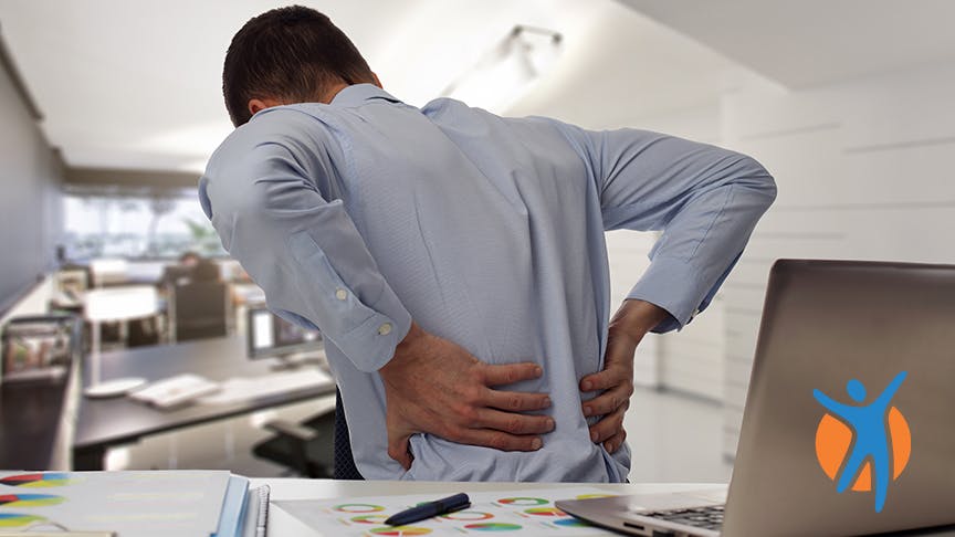 Man sitting in the office and holding his back in pain