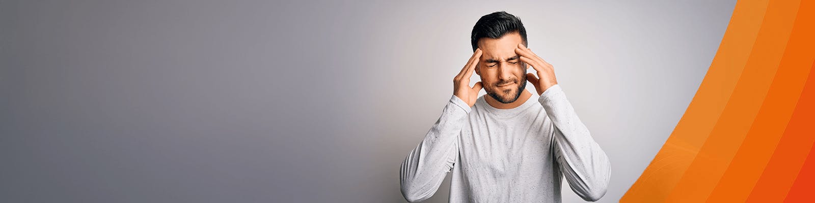 Mann Anfang Dreißig fasst sich mit seinen Händen an seine schmerzverzerrten Schläfen.