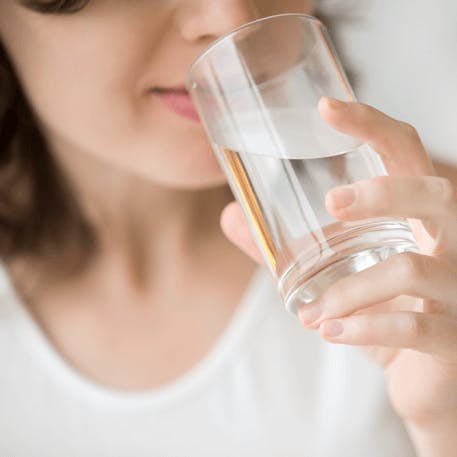 Frau mit einem Glas Wasser in der Hand.