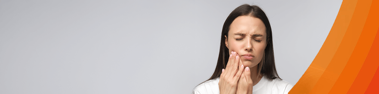 Frau mit Zahnschmerzen fasst sich an die Wange.