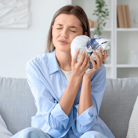 Frau mit Zahnschmerzen legt Kühlelement auf die schmerzende Stelle.