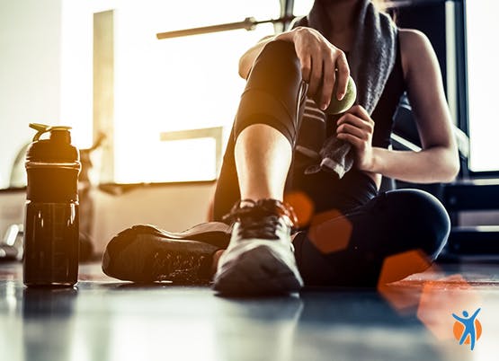 Woman with a hand on her knee while sitting on floor in gym