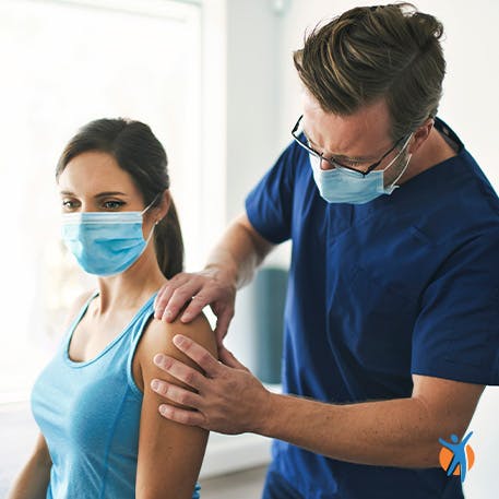 Physical therapist inspecting a woman's shoulder