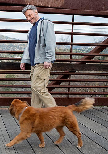 Smiling man taking his dog for a walk