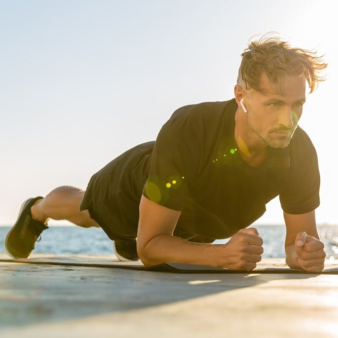 Homme exerçant en position de planche à l'extérieur