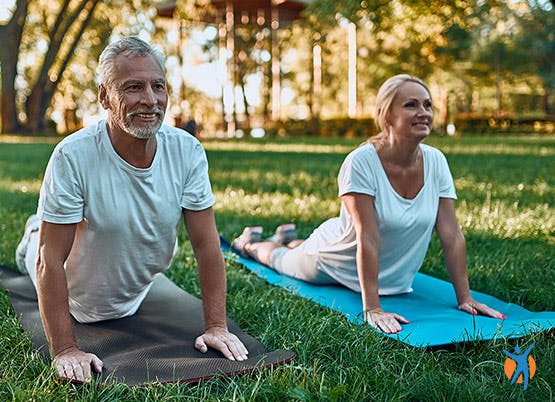 An elderly couple doing a back-stretching yoga poses - use these back exercises at home