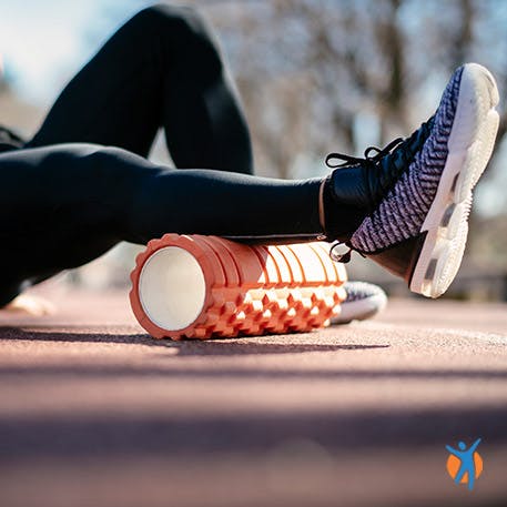 A runner using a foam roller to relieve pain in back muscles