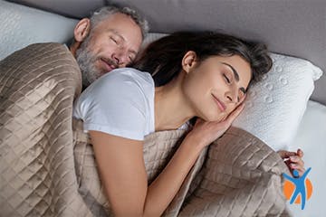 A couple sleeping in bed - a good nights sleep helps manage osteoarthritis