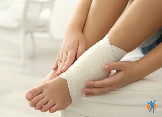 Woman compresses ankle pain with bandage as part of RICE method