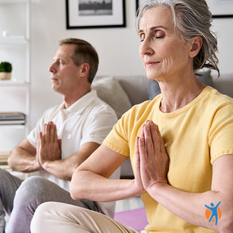Middle-aged couple stretching wrists in a seated yoga pose Middle-aged couple stretching wrists in a seated yoga pose