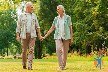 An older couple walking in the park - keeping moving is a great way to ease pain in the joints