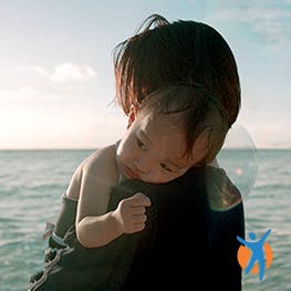 Mum hugging baby at the seaside - learn about pain relief while pregnant or breastfeeding
