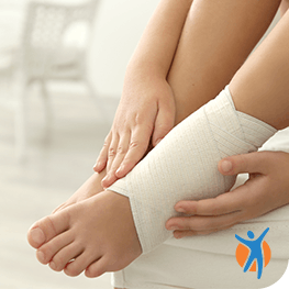 Woman compresses ankle pain with bandage as part of RICE method