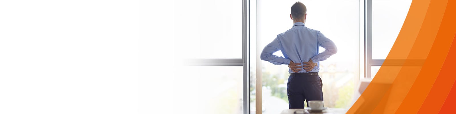 Main standing in an office holding his back due to lower back pain