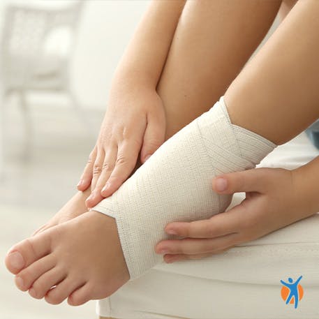 Person holding bandaged ankle - learn how RICE helps alleviate foot and ankle pain