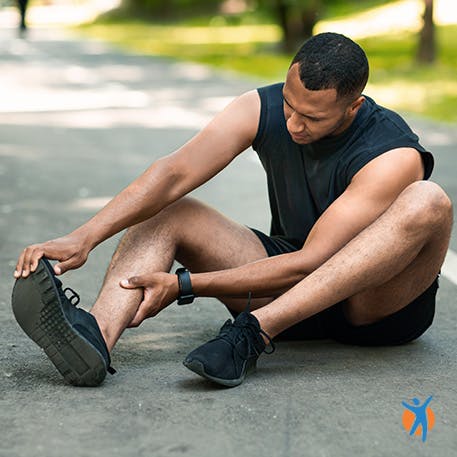 Man sitting in the road holding his calf due to heel and angle pain